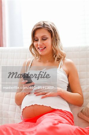 Happy pregnant woman reading sms