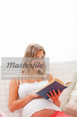 Young pregnant woman reading book