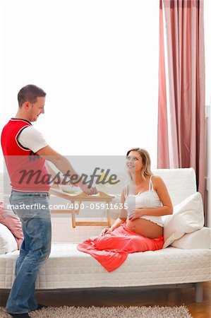 Young guy bring breakfast to happy pregnant wife