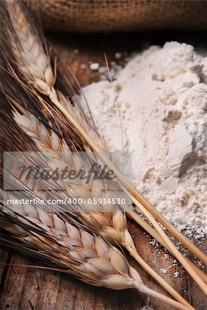 Wheat ears and flour sack on grunge wooden board