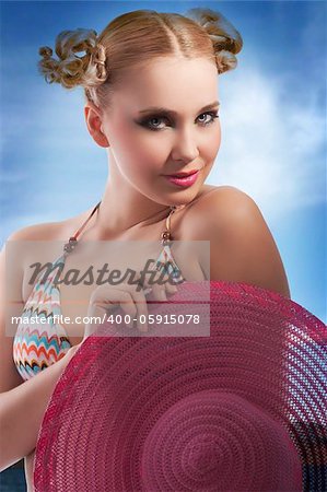 fashion shot of blond sensual girl in pink bikini and pareo taking pose with hat and hair style