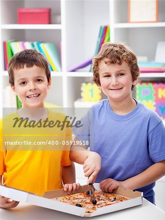 Happy boys cutting pizza in their room