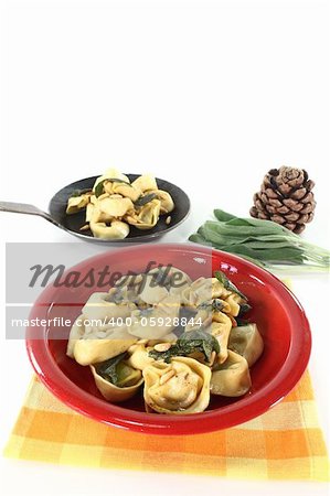 Arugula and ricotta tortellini with sage butter and pine nuts on a light background