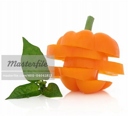 Sliced orange capsicum with leaf sprig over white background.
