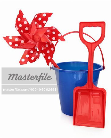 Blue plastic beach toy bucket, red spade and polka dot windmill over white background.