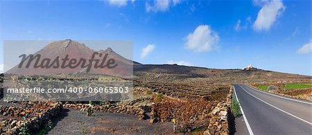 Empty road crossing the lava in the mountain, volcano backround. Panorama. Lanzarote, Canary islands, Spain