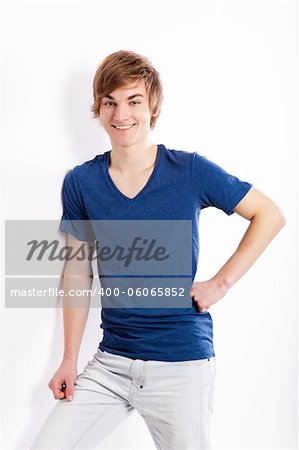 Portrait of a casual young man with a happy face, against a white wall