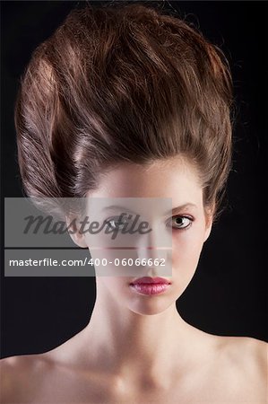 close up portrait of young beautiful woman with dark hair and creative hairstyle posing an black background