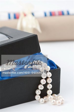 A string of matched cultivated pearls spilling out of a giftbox with a blue satin lining