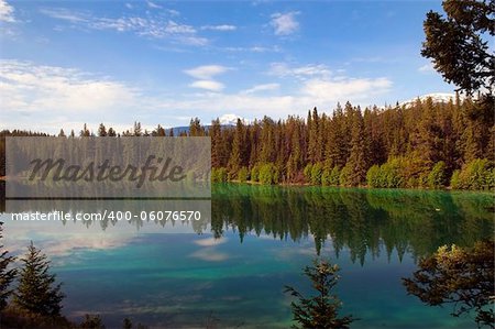 reflection of the sky and forests in the Emerald lake in Sabwatcha canyon, Canada
