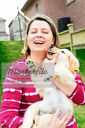 Portrait of laughing woman holding golden retriever puppy