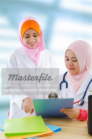 Two female Muslim doctor discussing on medical report