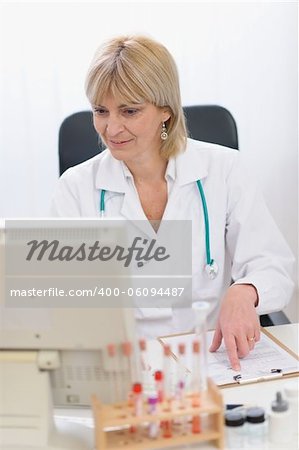 Portrait of smiling middle age doctor woman working on computer