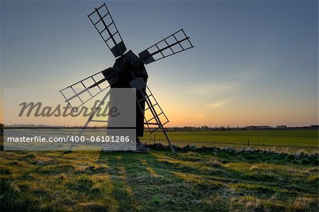 old windmill with the sun coming up in the background