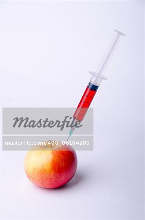 syringe with red liquid into red apple