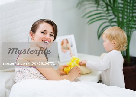 Mother playing with baby in bedroom