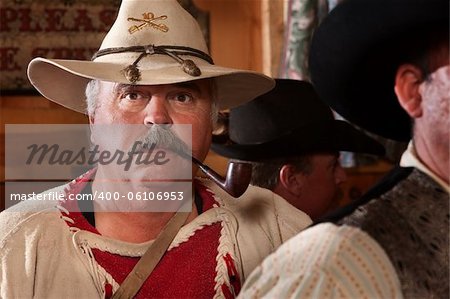 Big trapper with tobacco pipe in crowded saloon