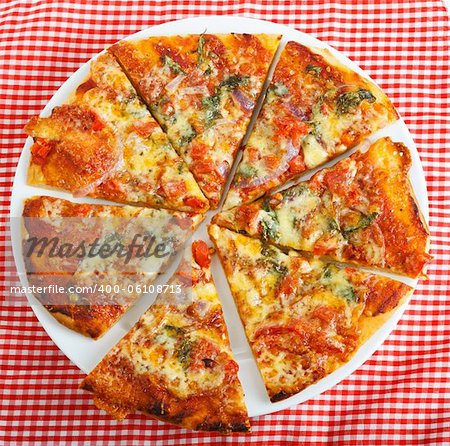 A delicious homemade round pizza on a red checkered table cloth