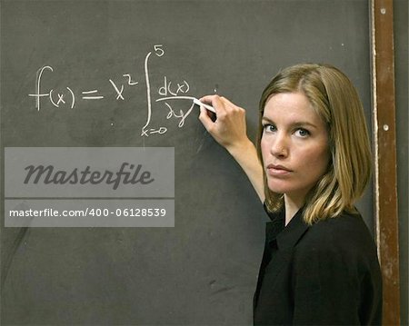 A woman writing a math equation on the black board.