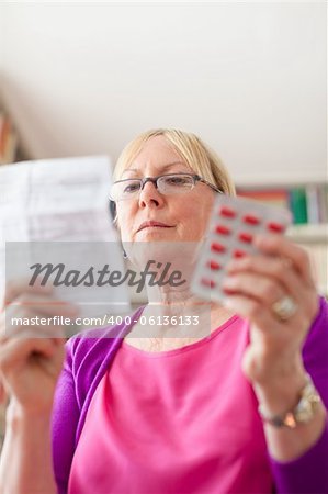 Elderly caucasian woman with medicine and reading drug prescription. Copy space
