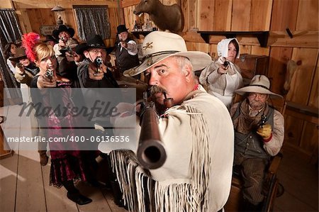 Tough old west desperado and group point their weapons in a bar