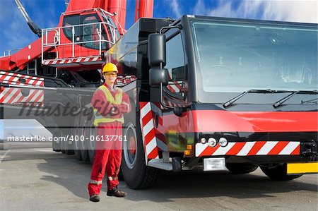 Crane driver, posing next to the huge mobile crane he's operating