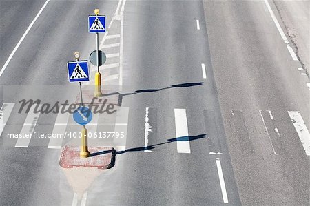 Zebra pattern pedestrian crossing with some road signs