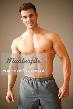 Portrait of a handsome young man with great physique posing on natural background