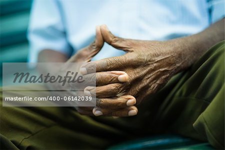 closeup of hands of elderly african american man sitting on bench