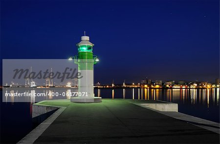 Late night at the port of Aarhus in Denmark with a lighthouse and cranes in the background