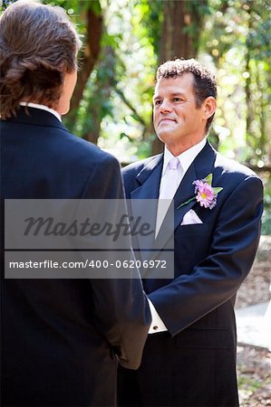 Handsome hispanic groom marrying his same sex partner in an outdoor wedding ceremony.