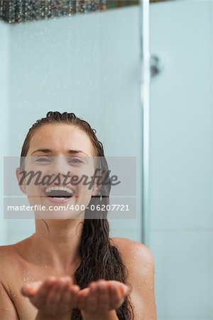 Happy woman catching water drops in shower under water jet