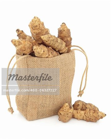 Jerusalem artichoke raw vegetables in a hessian drawstring sack and loose over white background.