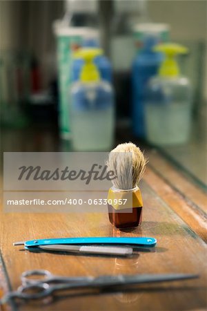 Closeup of barber tools, shaving brush, scissors and razor on shelf in barber shop