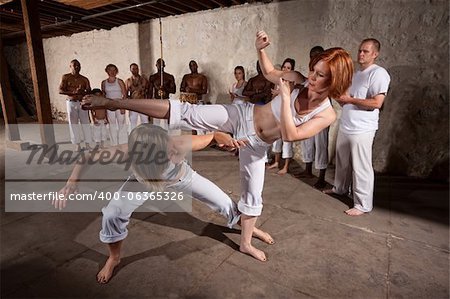 Capoeria martial artists performing techniques on concrete floor