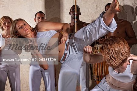 Female Capoeria fighters practing with team indoors