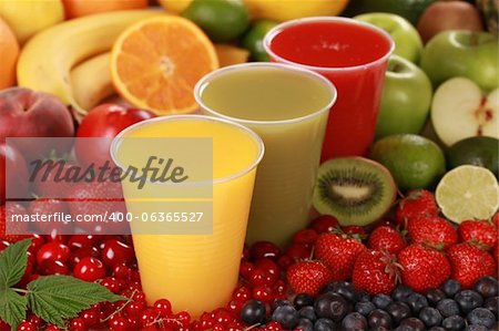Cups filled with different kinds of smoothies surrounded by fresh fruits