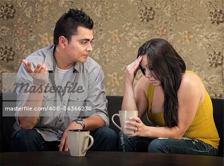 Depressed young Hispanic woman in conversation with man