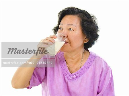 Asian senior woman drinking a glass of soy milk over white background