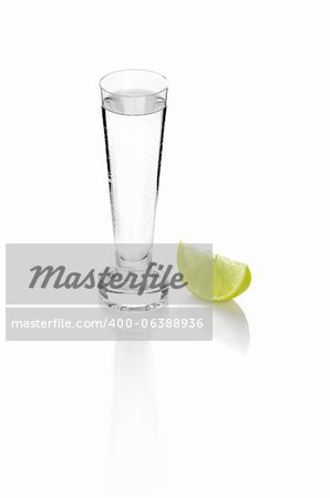 shot glass filled with clear cold alcohol isolated on white