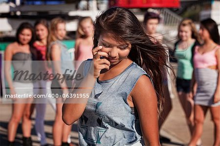 Shy teenage Filipino girl looking down with friends nearby