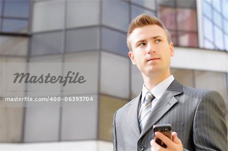 businessman holds the phone on the building background