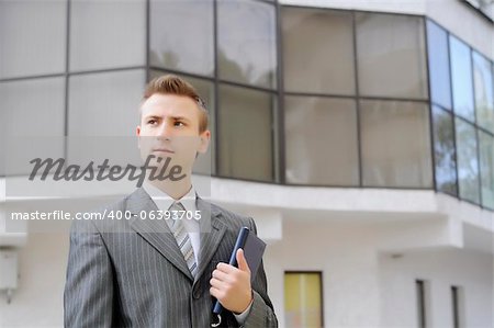 businessman holds the notebook on the building background