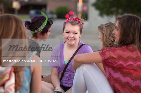 Cute smiling female student in purple sitting among friends