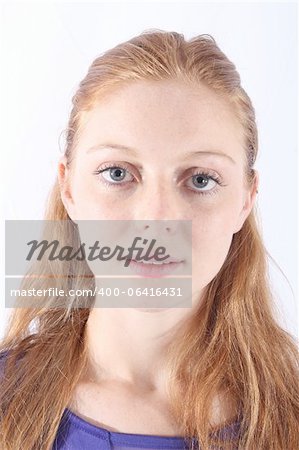 Young and beautiful redhead woman posing at the studio, with purple dress