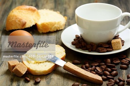 Coffee beans, eggs, bread and butter on a wooden table.