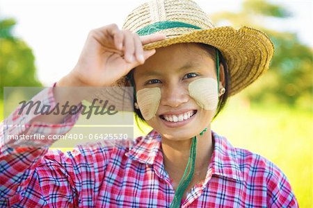 Portrait of a young Burmese woman with thanaka powdered face who works in the field