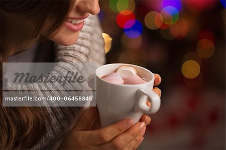 Closeup on hot chocolate with marshmallows in hand of happy woman