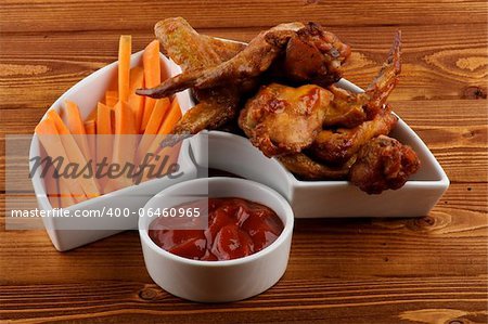 Chicken Wings, Carrot Sticks and Barbecue Dressing in White Bowls on Wood background