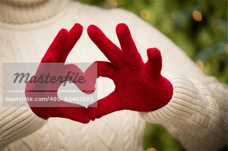 Woman in Sweater with Seasonal Red Mittens Holding Out a Heart Sign with Her Hands.